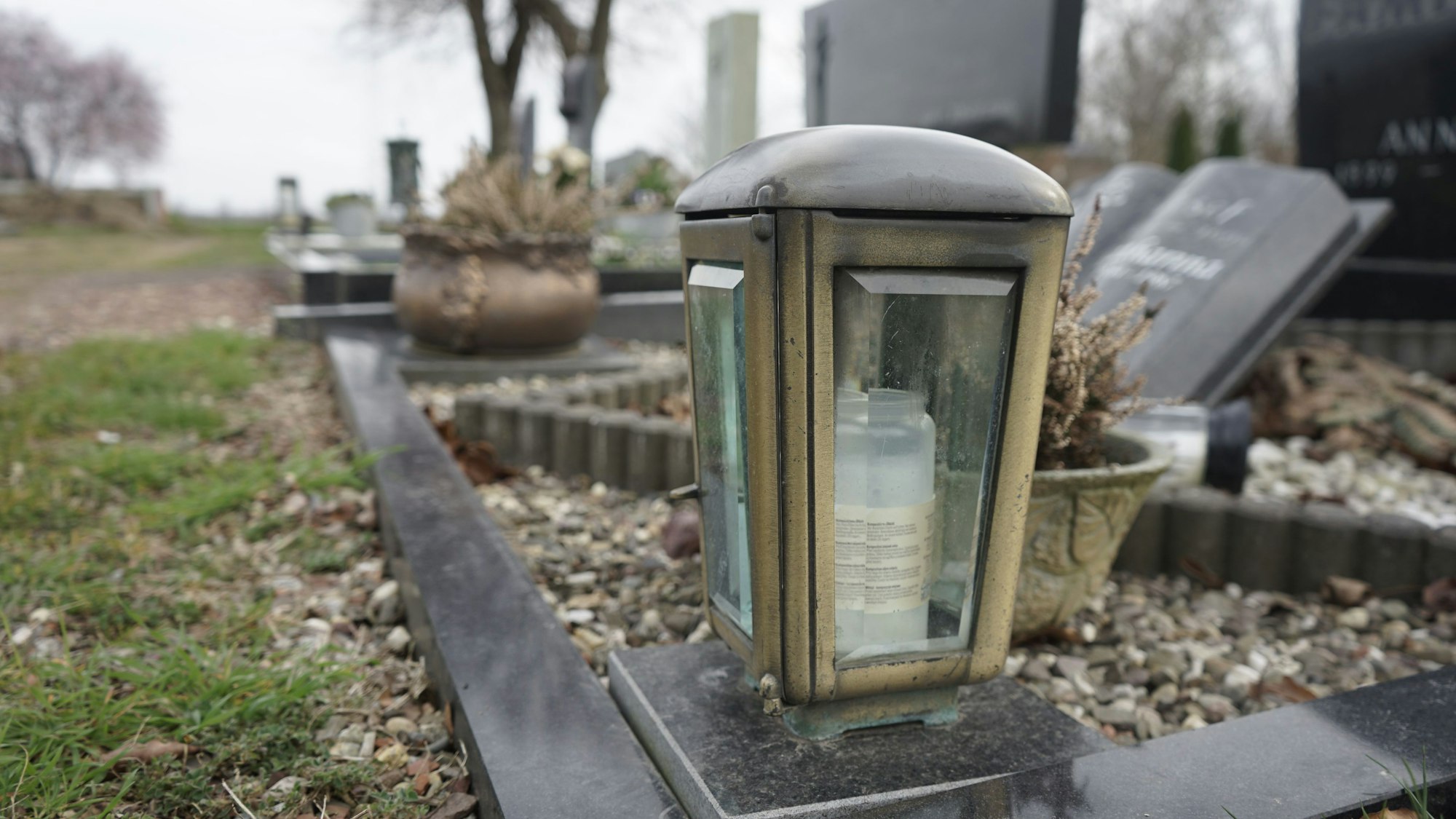 Eine Grablampe auf der Einfassung eines Grabes.