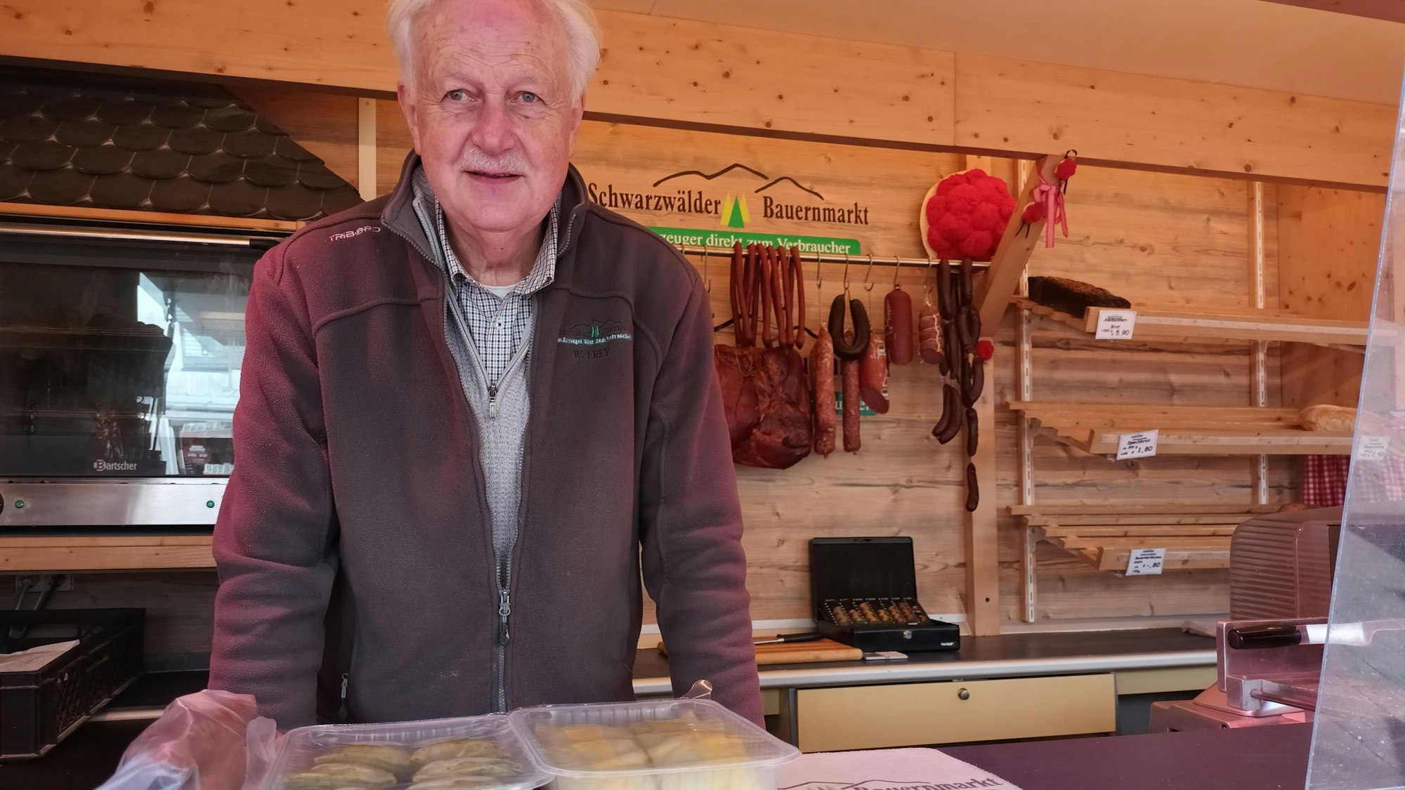 Ein Mann in einem Verkaufsladen für Wurst, Brot und Käse