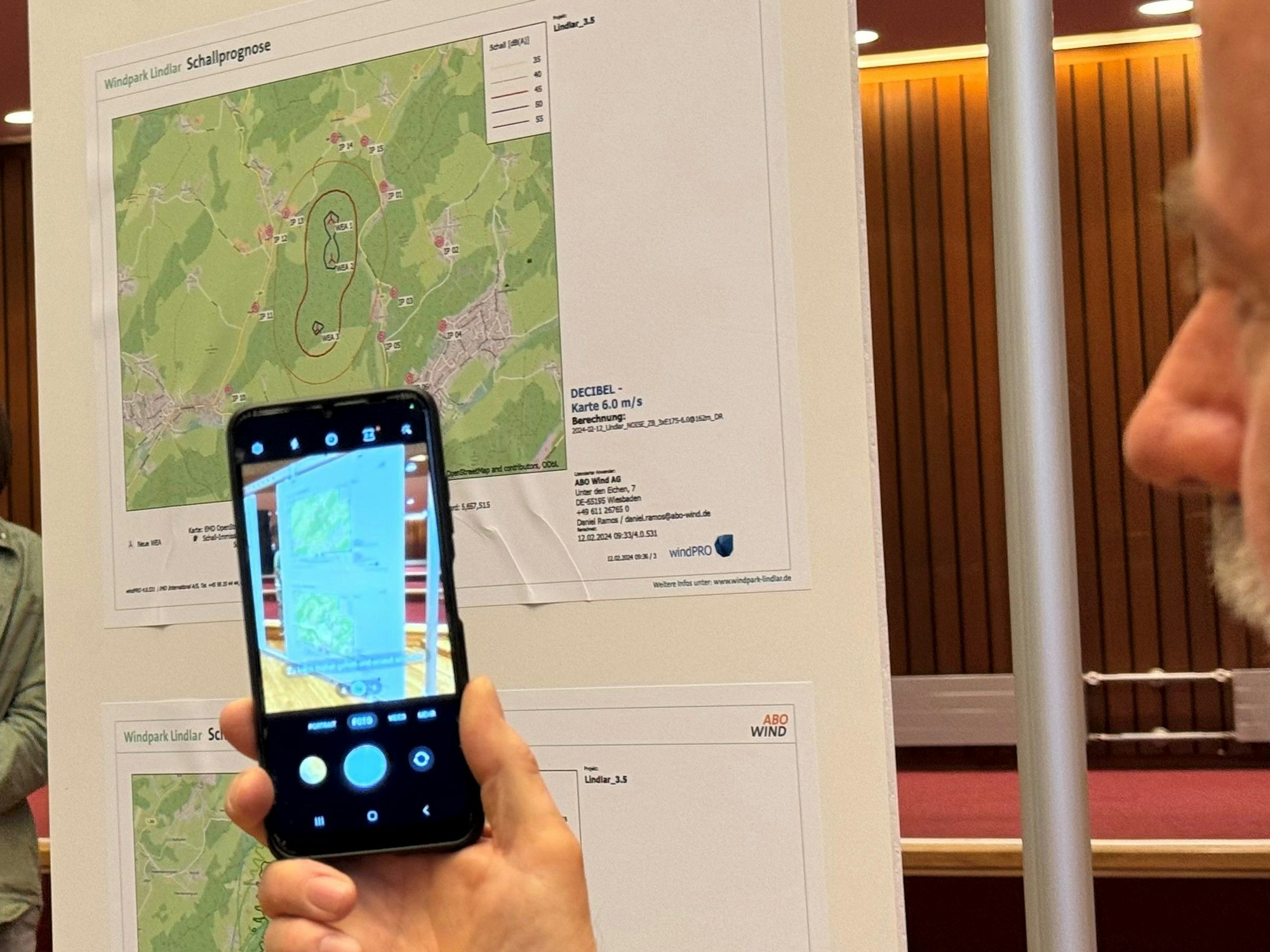 Eine Hand hält ein Smartphone, auf dem Display ist ein Foto einer Landkarte zu sehen.