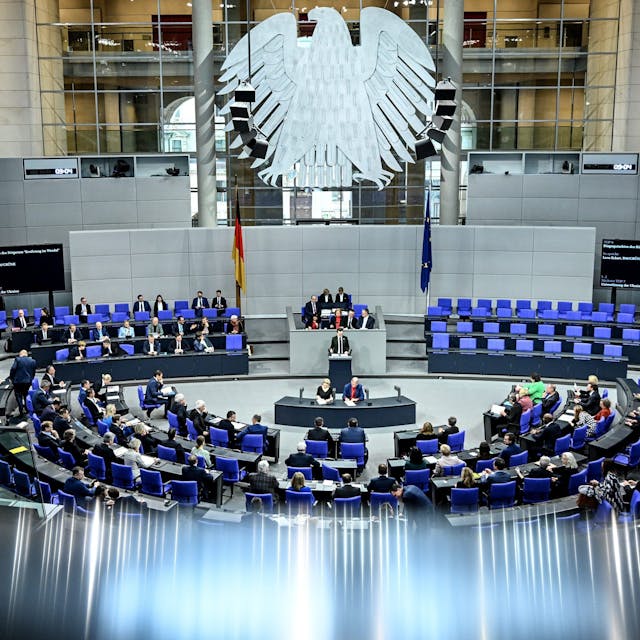 Die Abgeordneten des Bundestags stimmen über die Lieferungen von Taurus-Marschflugkörpern an die Ukraine ab. Mehrere Abgeordnete sitzen auf den blauen Sitzen im Plenum des Bundestags.