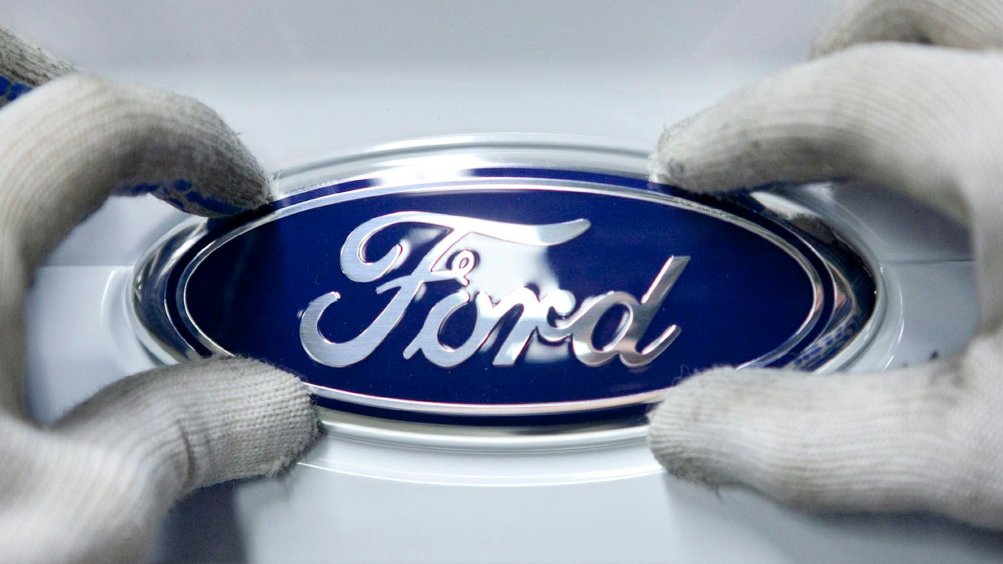 Eine Mitarbeiterin montiert im Ford-Werk Saarlouis an einem neuen Ford-Focus das Logo von Ford auf der Heckklappe.