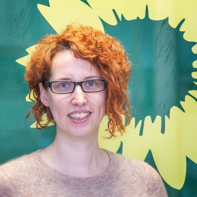 Porträt einer Frau vor dem Symbol der Grünen.
