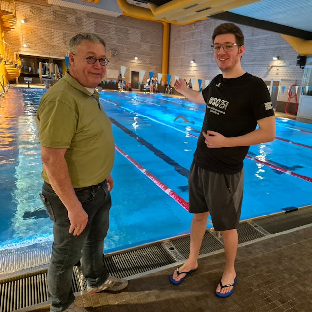 Bild von zwei Männern, im Hintergrund ein Schwimmbecken