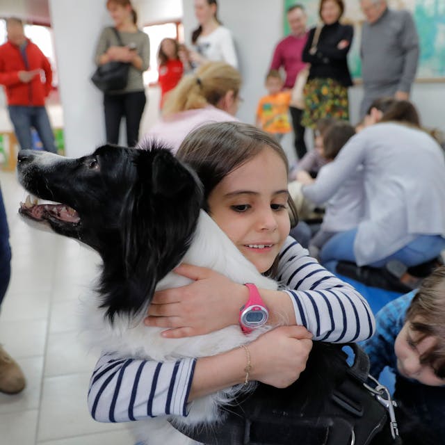 Das Foto zeigt ein Kind, das einen Hund umarmt.
