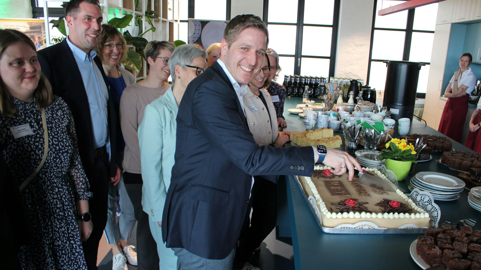 Markus Ramers schneidet eine Torte an, um ihn herum steht das Team der Nordeifel-Tourismus GmbH.