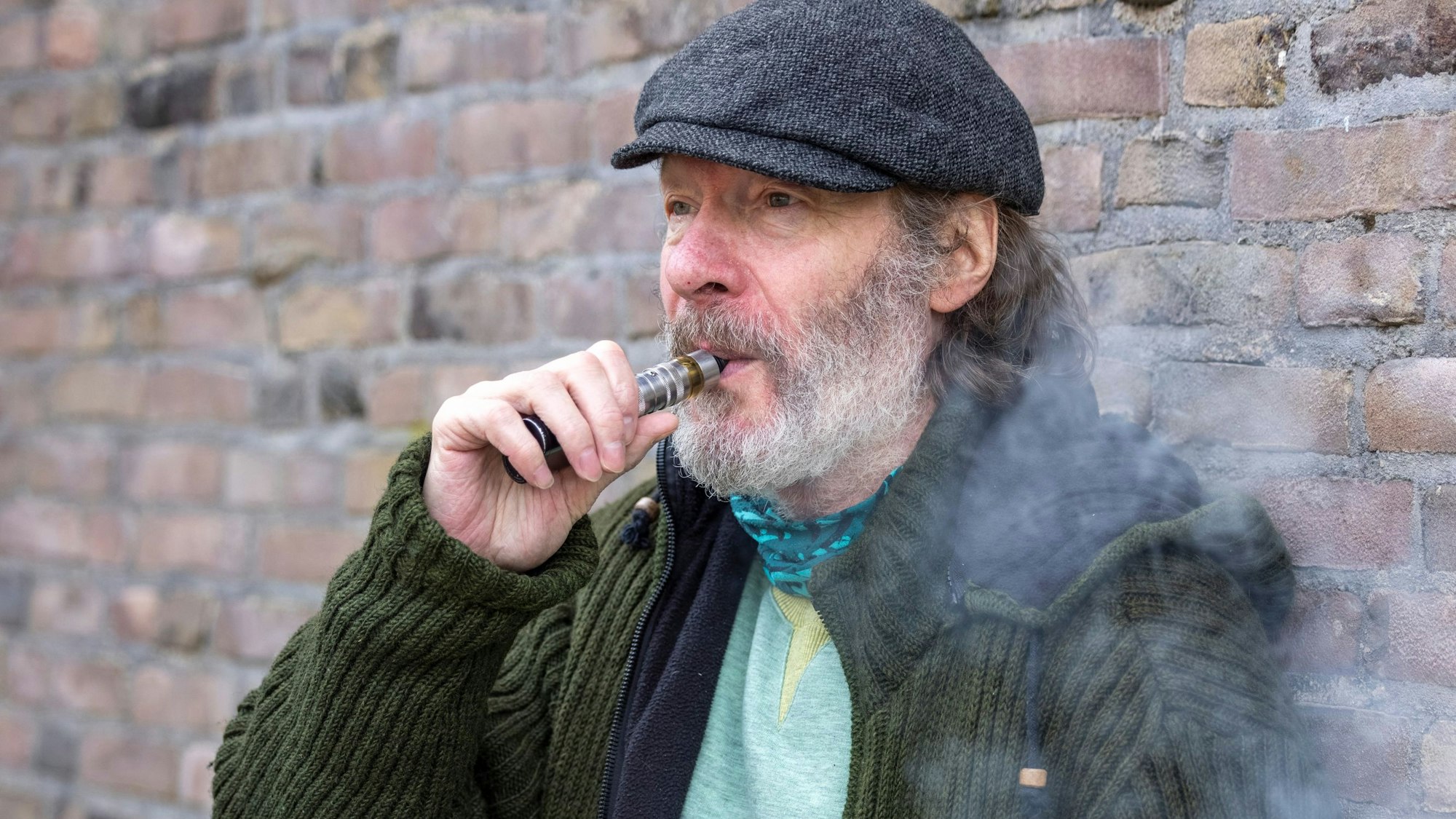 Gerd Köster steht an einer Wand und zieht an einer E-Zigarette.