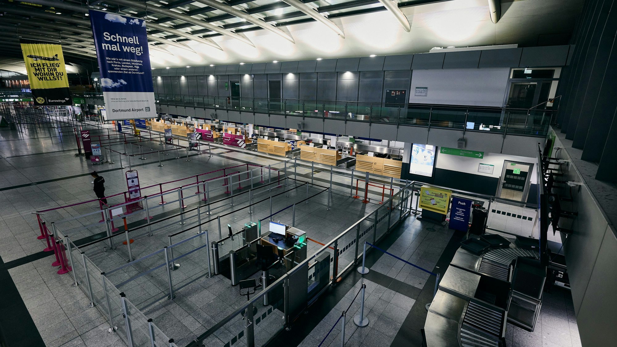 Ein Flughafenmitarbeiter steht in der menschenleeren Abflughalle am Flughafen Düsseldorf. (Symbolbild)