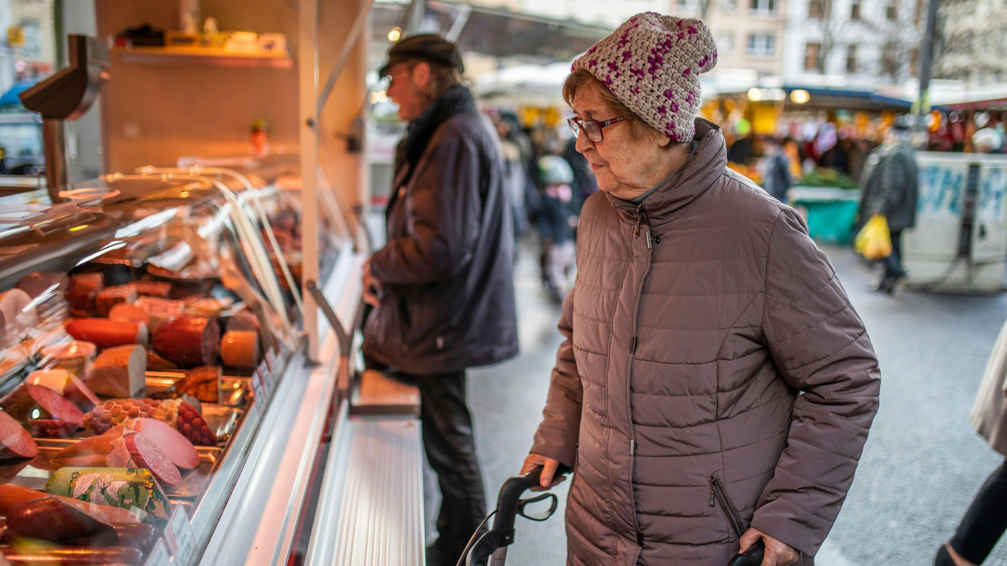 Eine Frau betrachtet die Wurstwaren eines Metzgers auf einem Kölner Wochenmarkt. (Archivbild)
