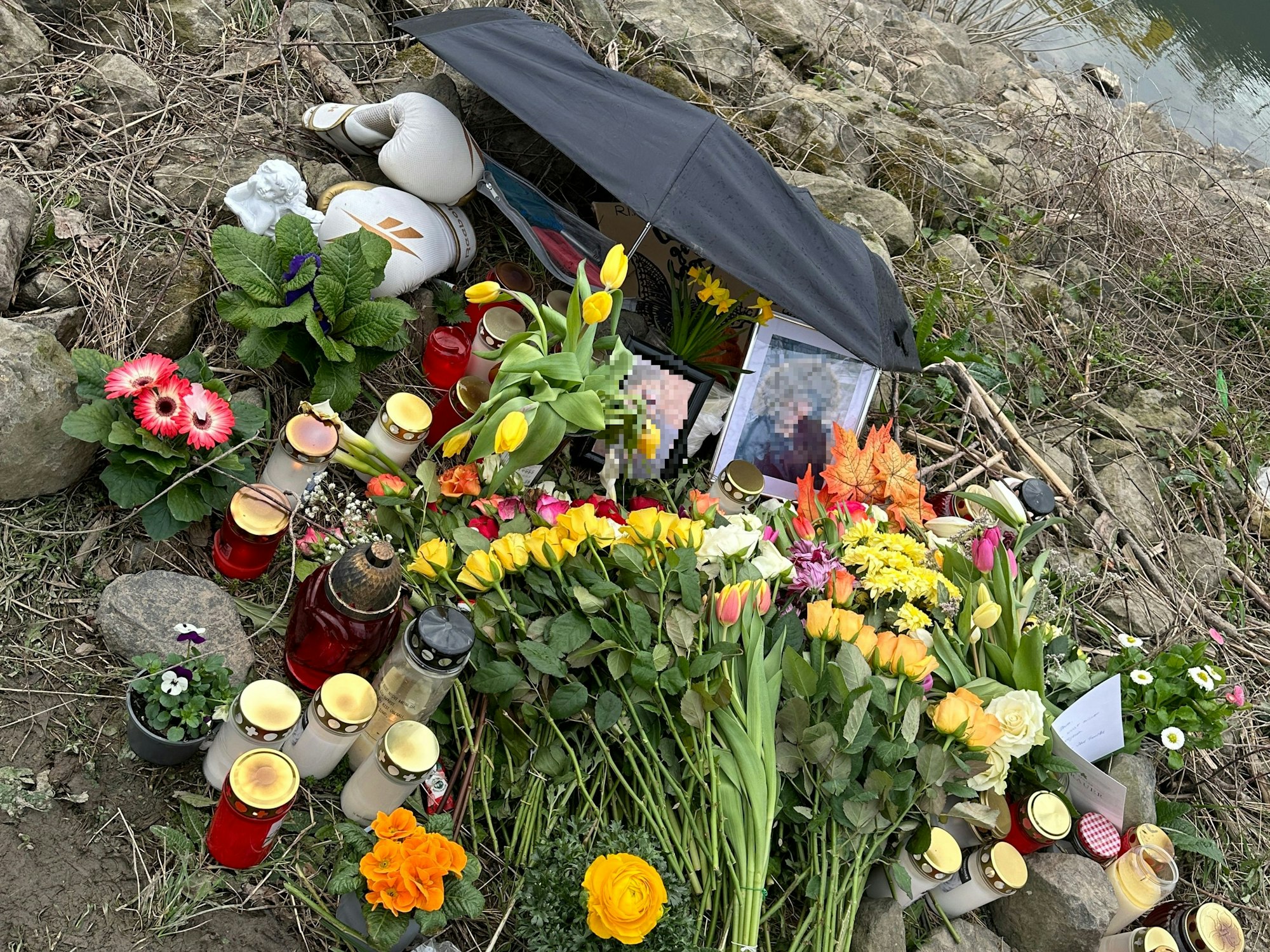 Blumen und Kerzen sind am Fundort der Leiche in Köln-Mülheim zu sehen.