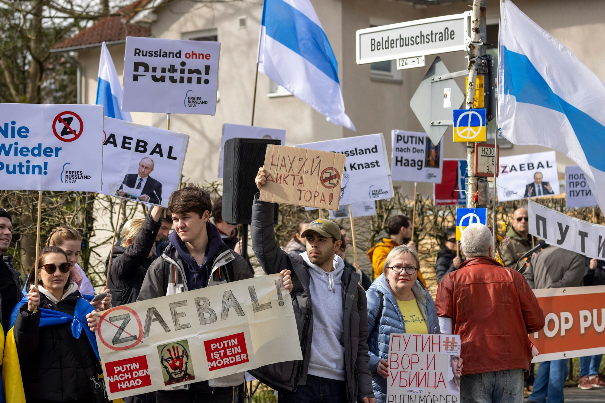 Demonstrantinnen und Demonstranten stehen auf der anderen Straßenseite des russischen Generalkonsulats und protestieren gegen Präsident Putin.