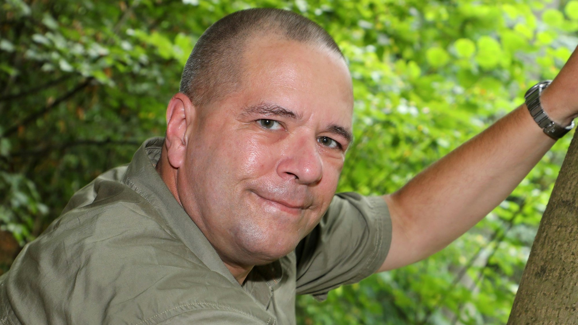 Wolfsberater Dietmar Birkhahn steht in einem Wald an einem Baum.