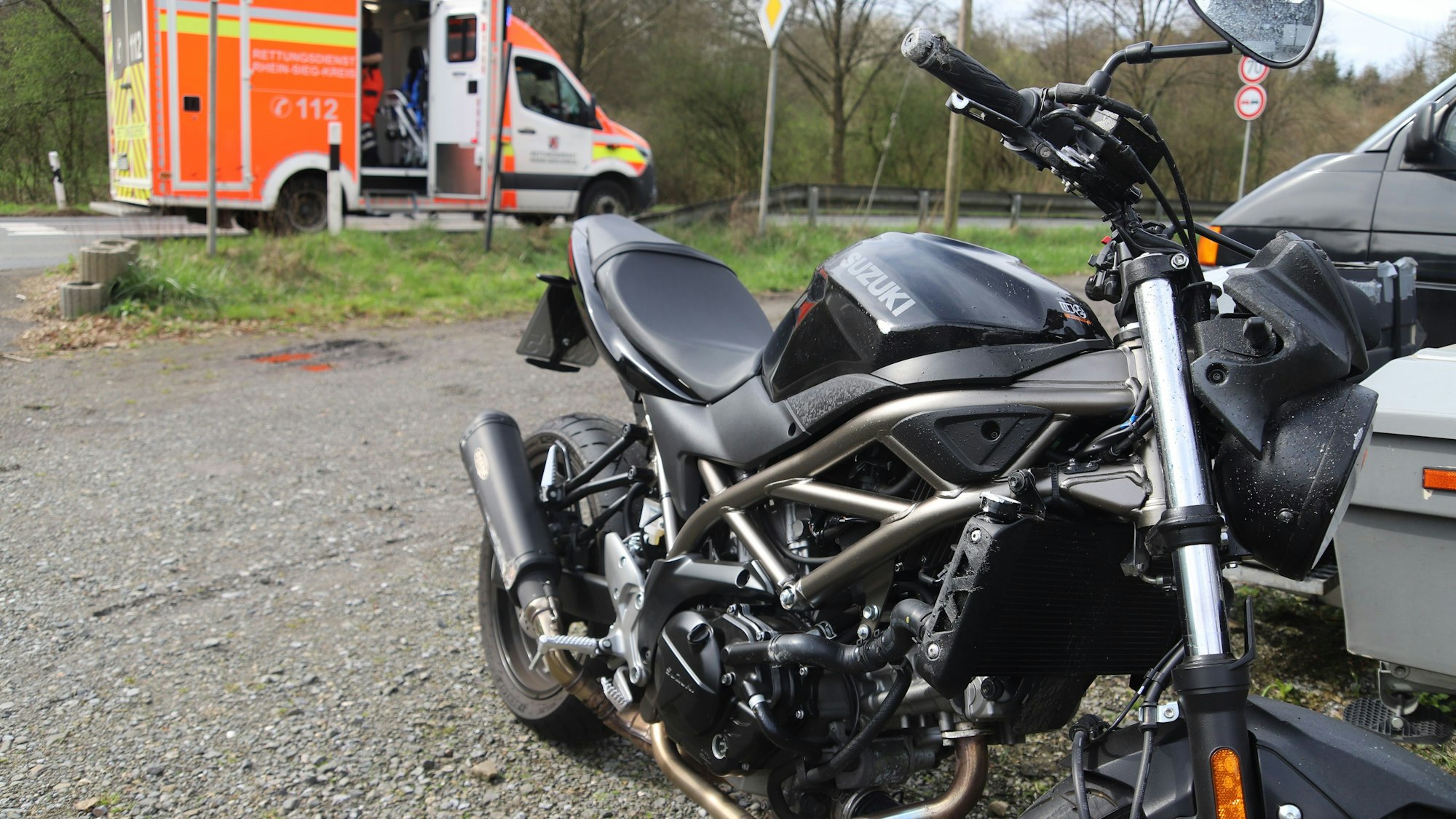 Ein schwarzes Motorrad steht in der Nähe eines Rettungswagens.