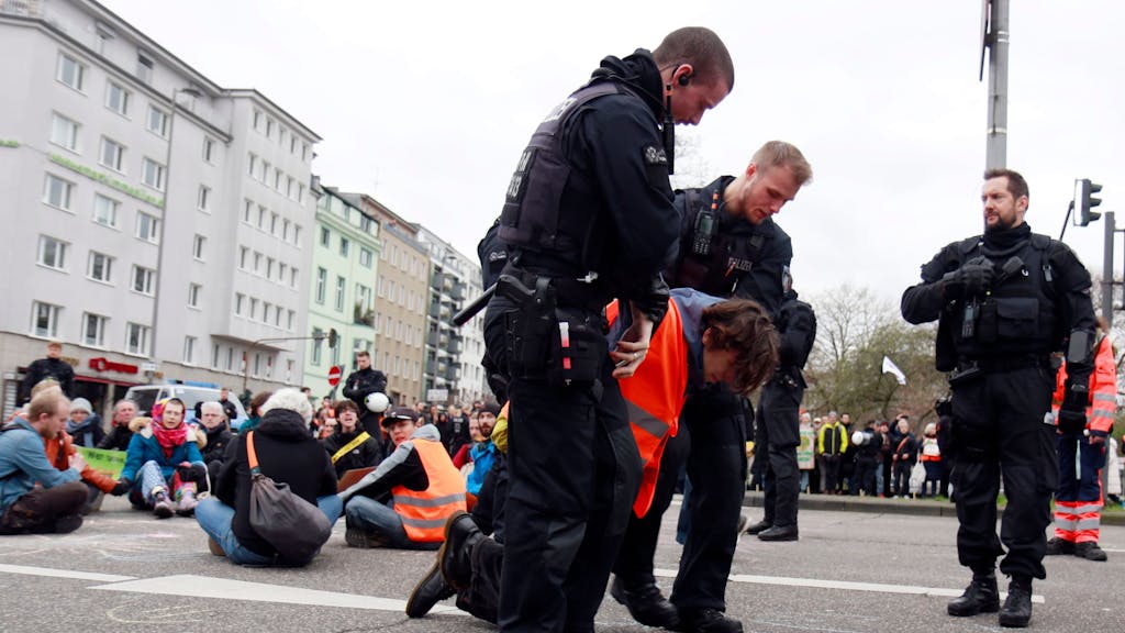 Polizisten tragen einen Demonstranten von der Straße.