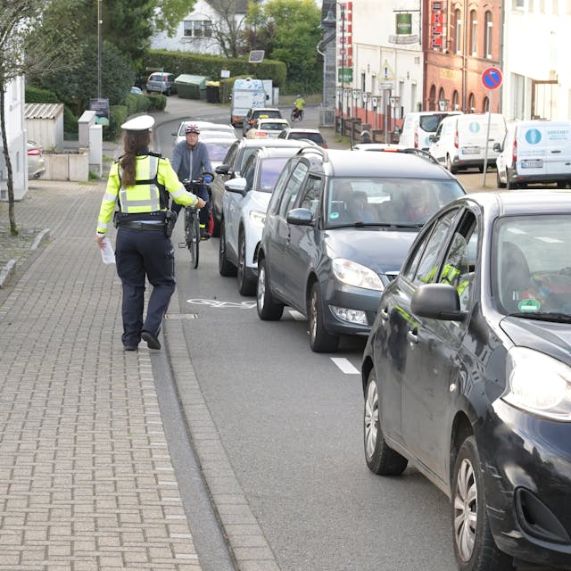Bei der Aktion "Mehr Miteinander im Verkehr" beobachtet eine Polizistin den Rad-Schutzstreifen 
auf der Bensberger Straße in Forsbach.