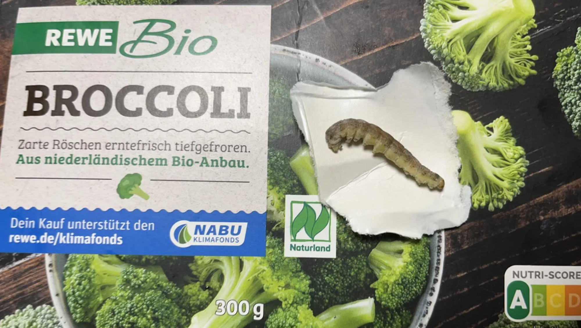 Eine Raupe liegt auf der Broccoli-Verpackung.