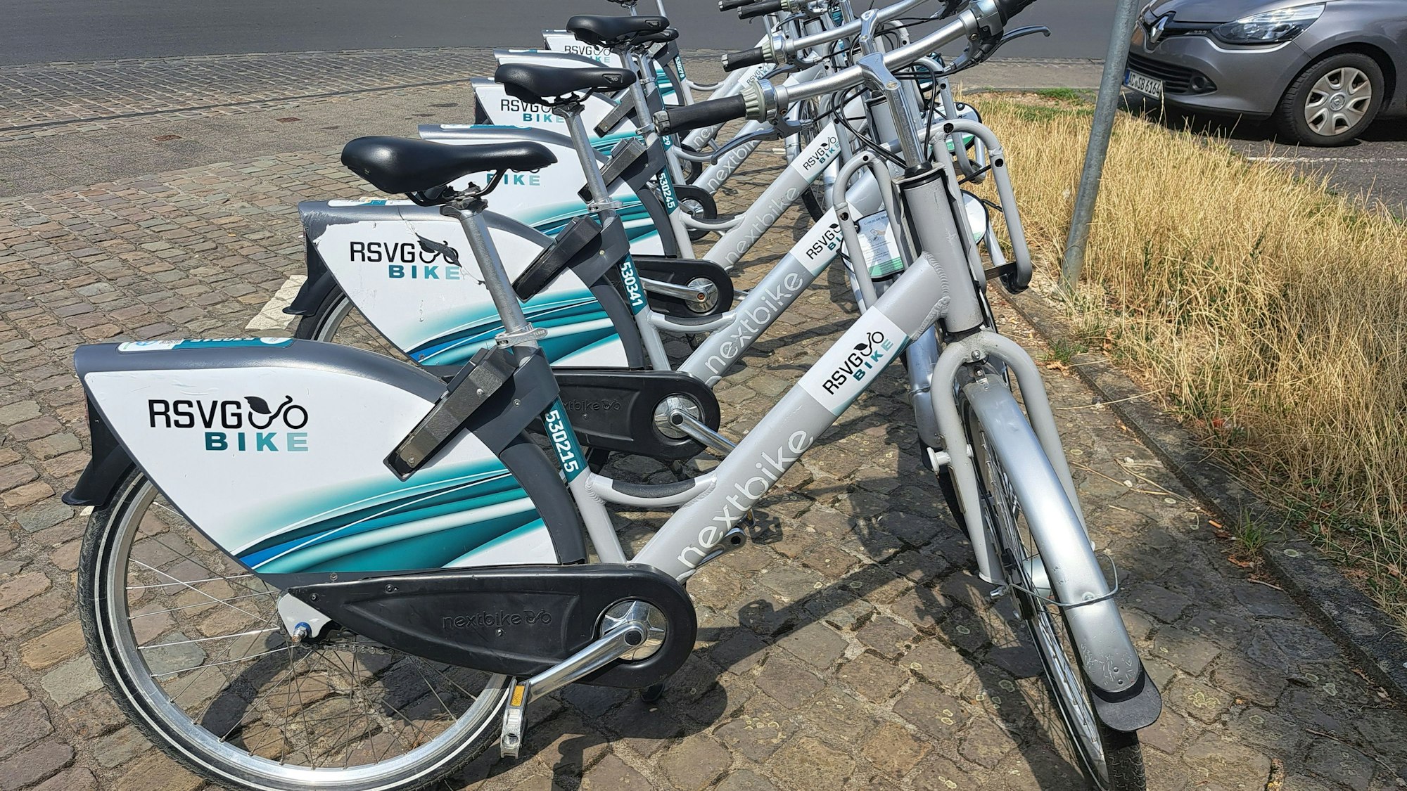 Mehrere graue Fahrräder mit einem großen Hinterradschutz, auf dem der Schriftzug RSVG-Bike steht.