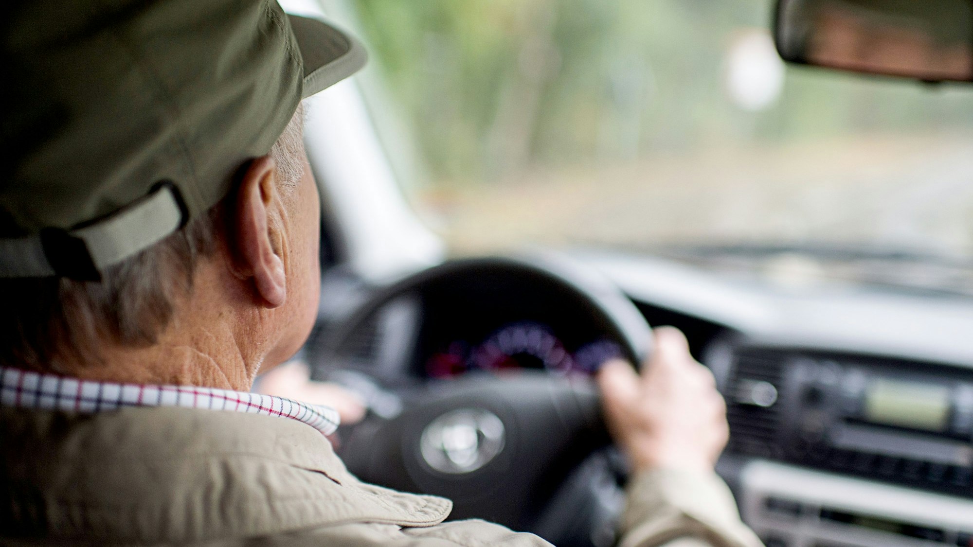 Ein älterer Mann sitzt am Steuer eines Autos.