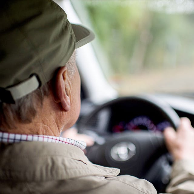 Ein älterer Mann sitzt am Steuer eines Autos.