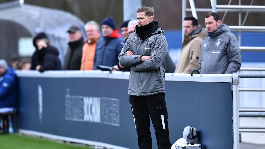 Trainer der U19 von Borussia Mönchengladbach verschränkt die Arme in der Coaching-Zone.