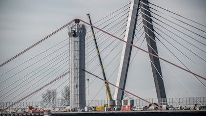 Der Abbruch der alten Autobahnbrücke läuft: Von den alten Pylonen wurde oben die Verkleidung abgenommen, die gerundeten Seilsättel sind seither sichtbar. Der Stahl ist mit bleihaltigem Schutzanstrich versehen.