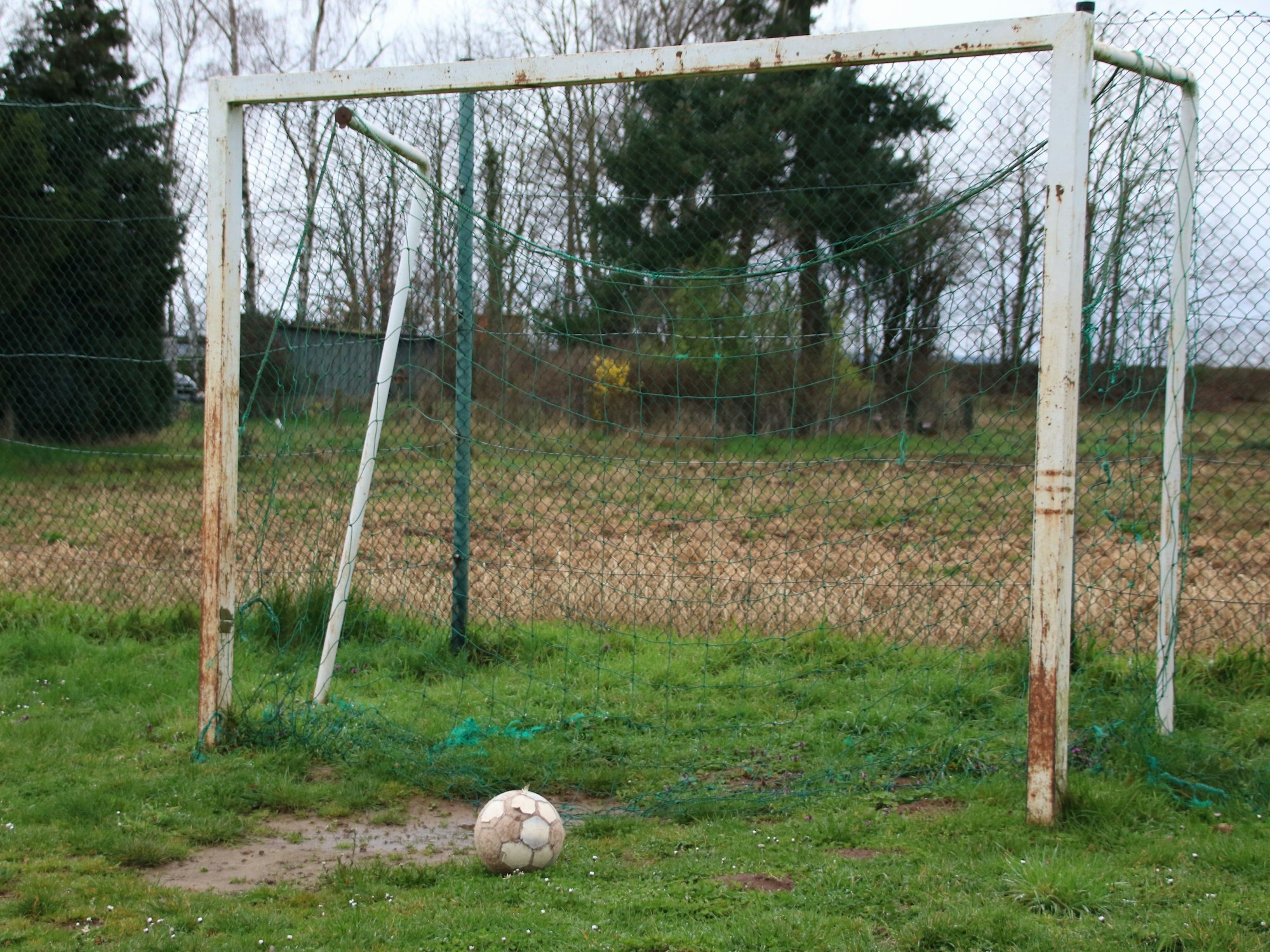 Das Bild zeigt ein kleines Fußballtor, das an den Pfosten rostet.