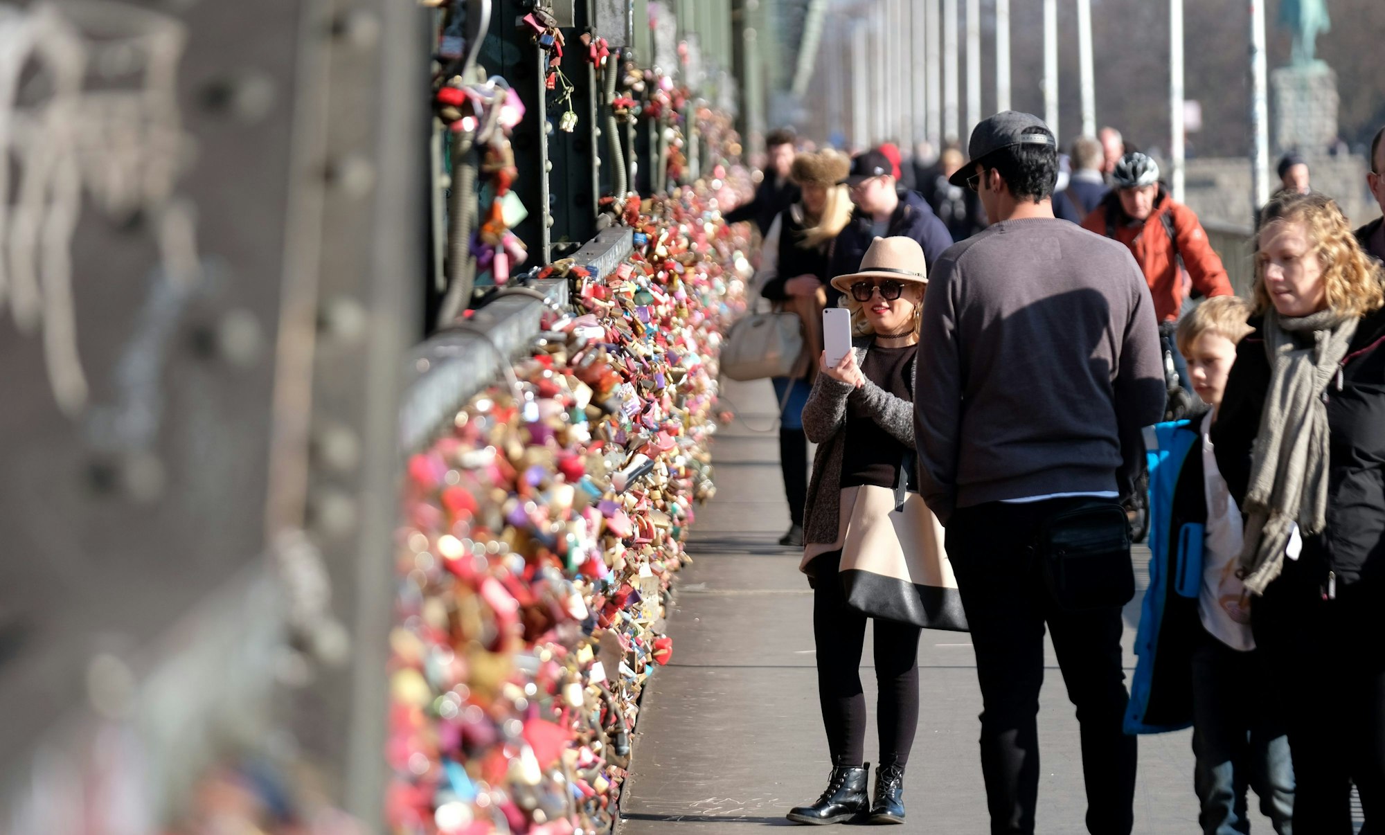 Menschen betrachten die Liebesschlösser an der Hohenzollernbrücke.
