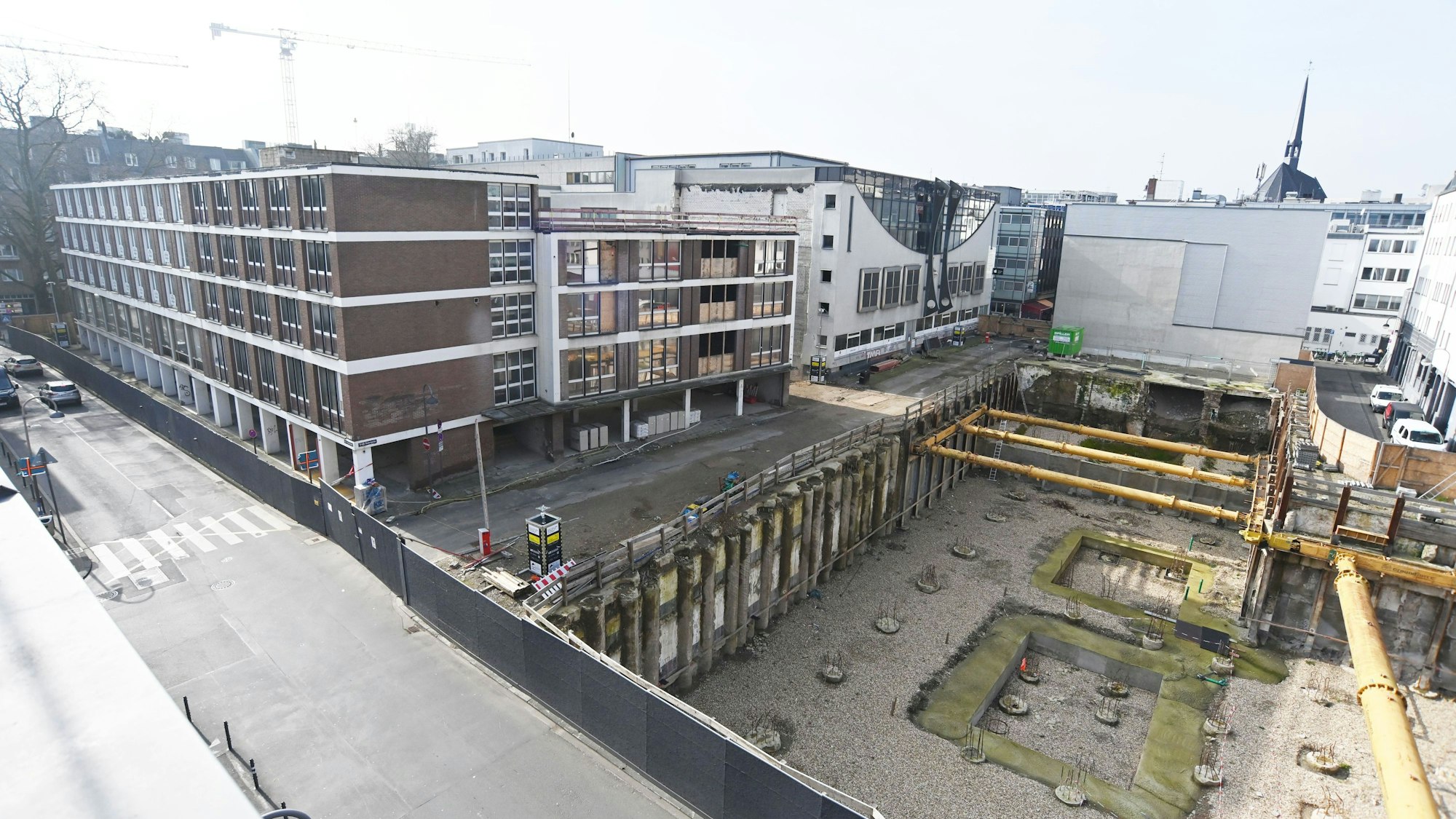 Das Bild zeigt eine Baustelle mit mehreren Gebäuden und einer Baugrube.