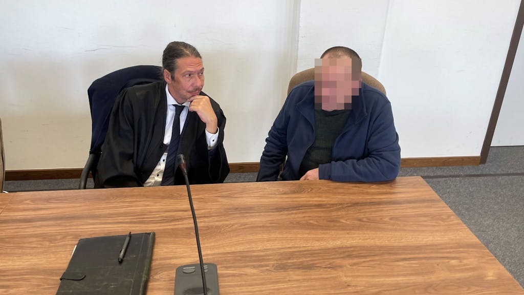 Ein Mann sitzt neben seinem Anwalt auf der Anklagebank,