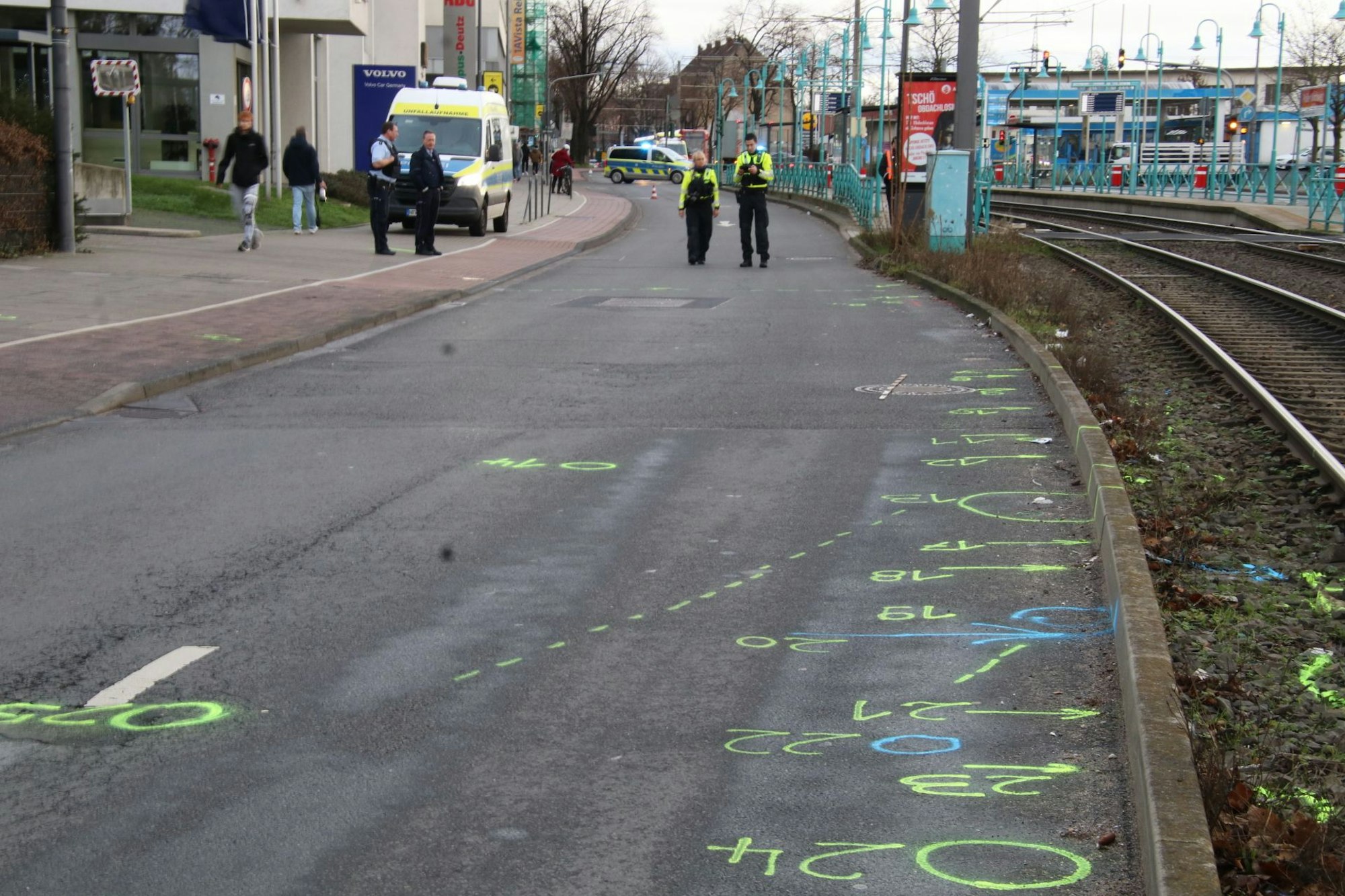 Die Polizei ist auf einer Straße im Einsatz, hat dort mit Kreisen, Pfeilen und Ziffern Spuren markiert.