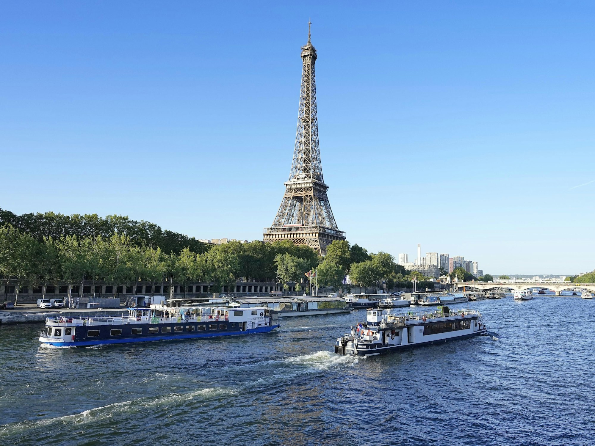 Ein Boot und ein Lastkahn fahren vor dem Eiffelturm auf der Seine während eines Tests für die Eröffnungsfeier der Olympischen Spiele 2024 in Paris. Für die Eröffnungsfeier der Spiele am 26. Juli 2024 sind Tausende von Olympioniken auf rund 160 Booten auf dem Fluss geplant.