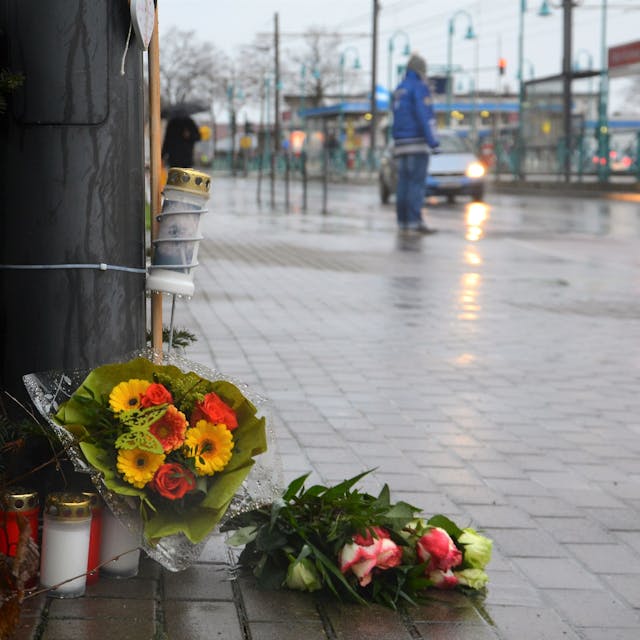Kerzen und Blumen liegen auf der Siegburger Straße an der Stelle, wo ein Fußgänger im Januar 2023 von einem Auto überfahren wurde.&nbsp;