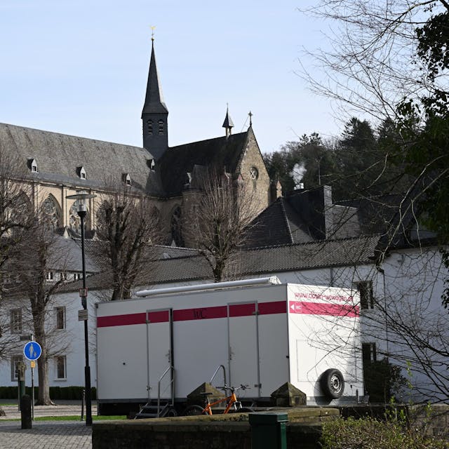 Ein mobiler Toilettenwagen steht vor der Jugendbildungsstätte Haus Altenberg. Im Hintergrund der Altenberger Dom.