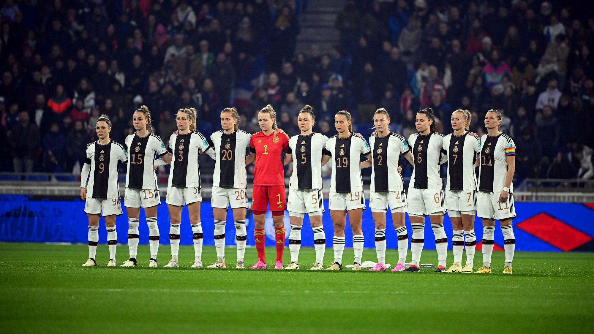 Die Frauen der deutschen Nationalmannschaft stehen Arm in Arm vor dem Spiel am Mittelkreis.