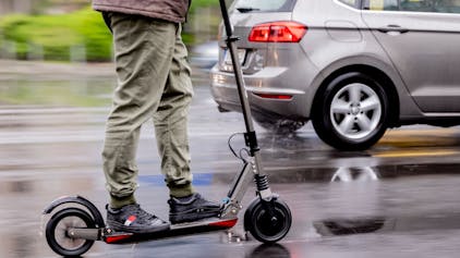 Ein Mann fährt mit einem E-Scooter auf der Straße.&nbsp;