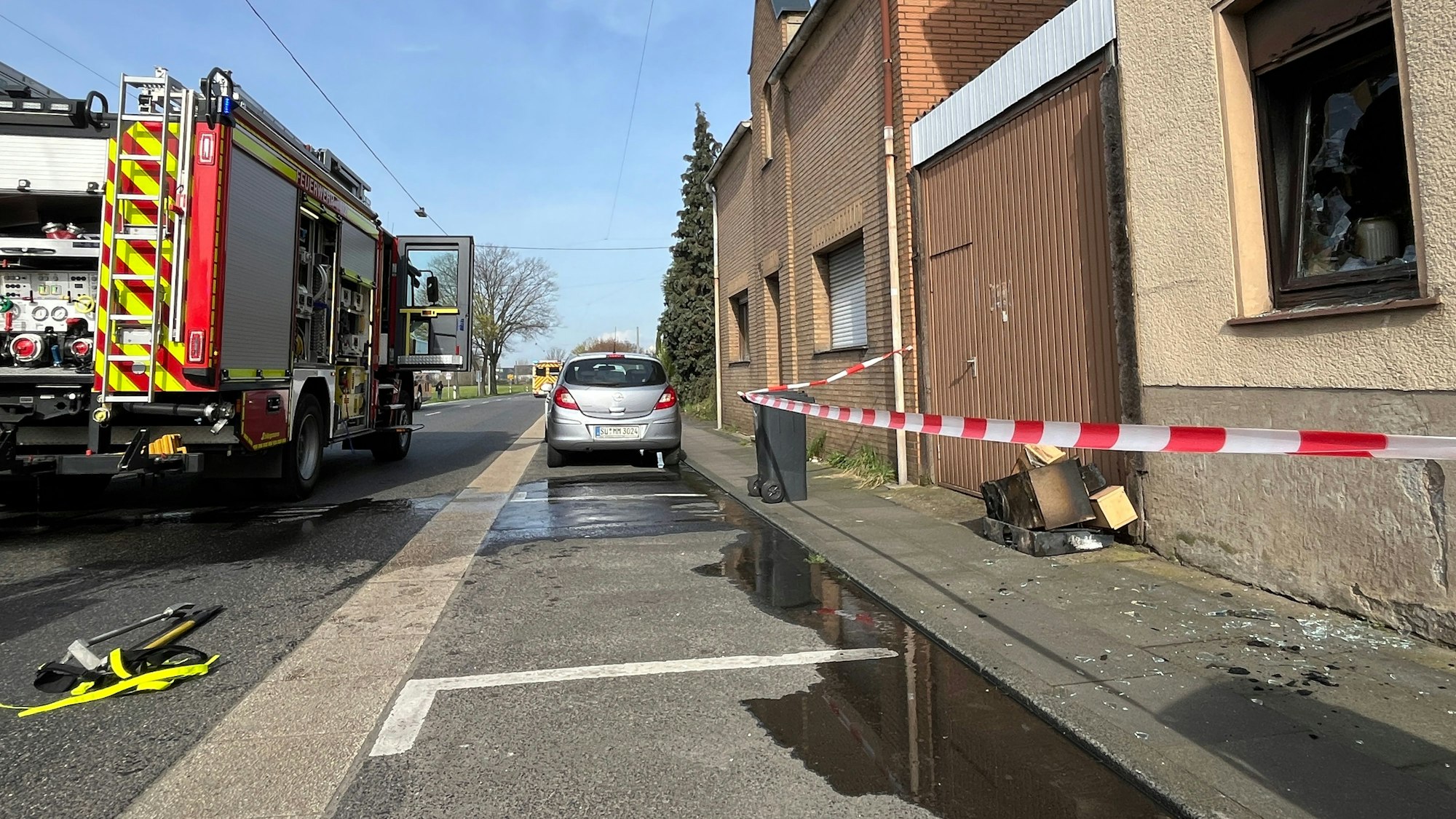 In einem Haus an der Hauptstraße in Troisdorf-Spich hat eine Küche gebrannt, Feuerwehrleute brachten die verbrannten Möbel ins Freie und sperrten den Bürgersteig mit Flatterband.