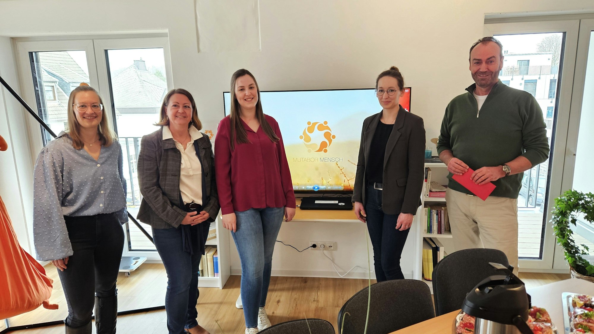 Juliane Herf (v.l.), Alexandra Fischer, Melanie Thiel, Veronika Scheipers und Jürgen Sellge stehen vor einem Bildschirm mit dem Symbol von Mutabor.