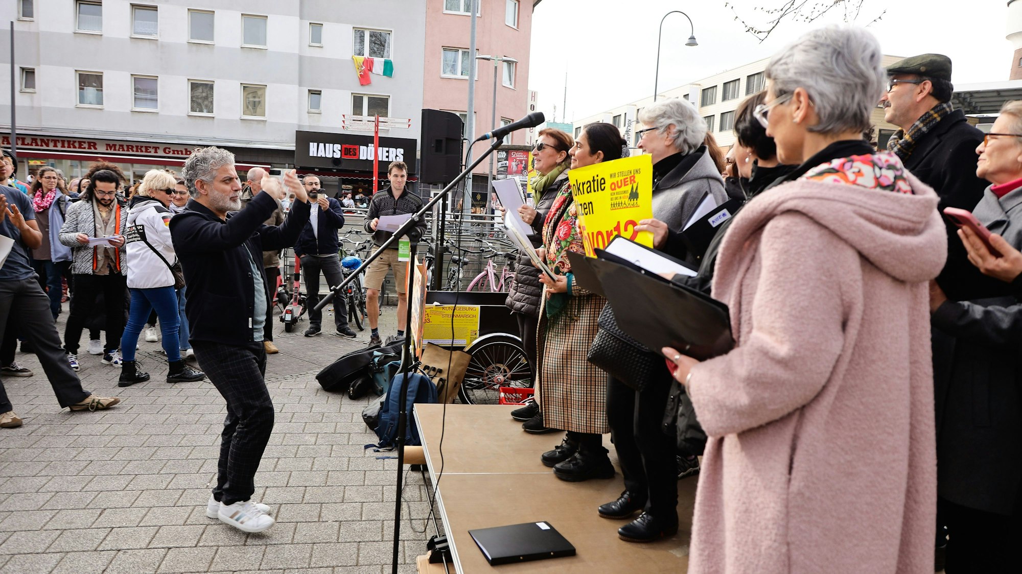Menschen bei einer Demonstration stehen auf einer Bühne vor einem Mikrofon.