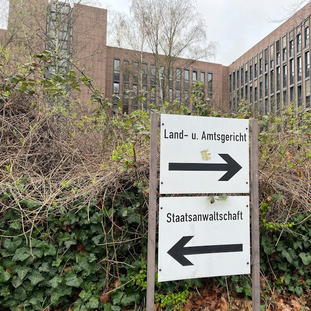 Auf dem Foto ist ein Schild vor dem Kölner Gerichtszentrum zu sehen, das auf das Land- und Amtsgericht sowie die Staatsanwaltschaft hinweist.