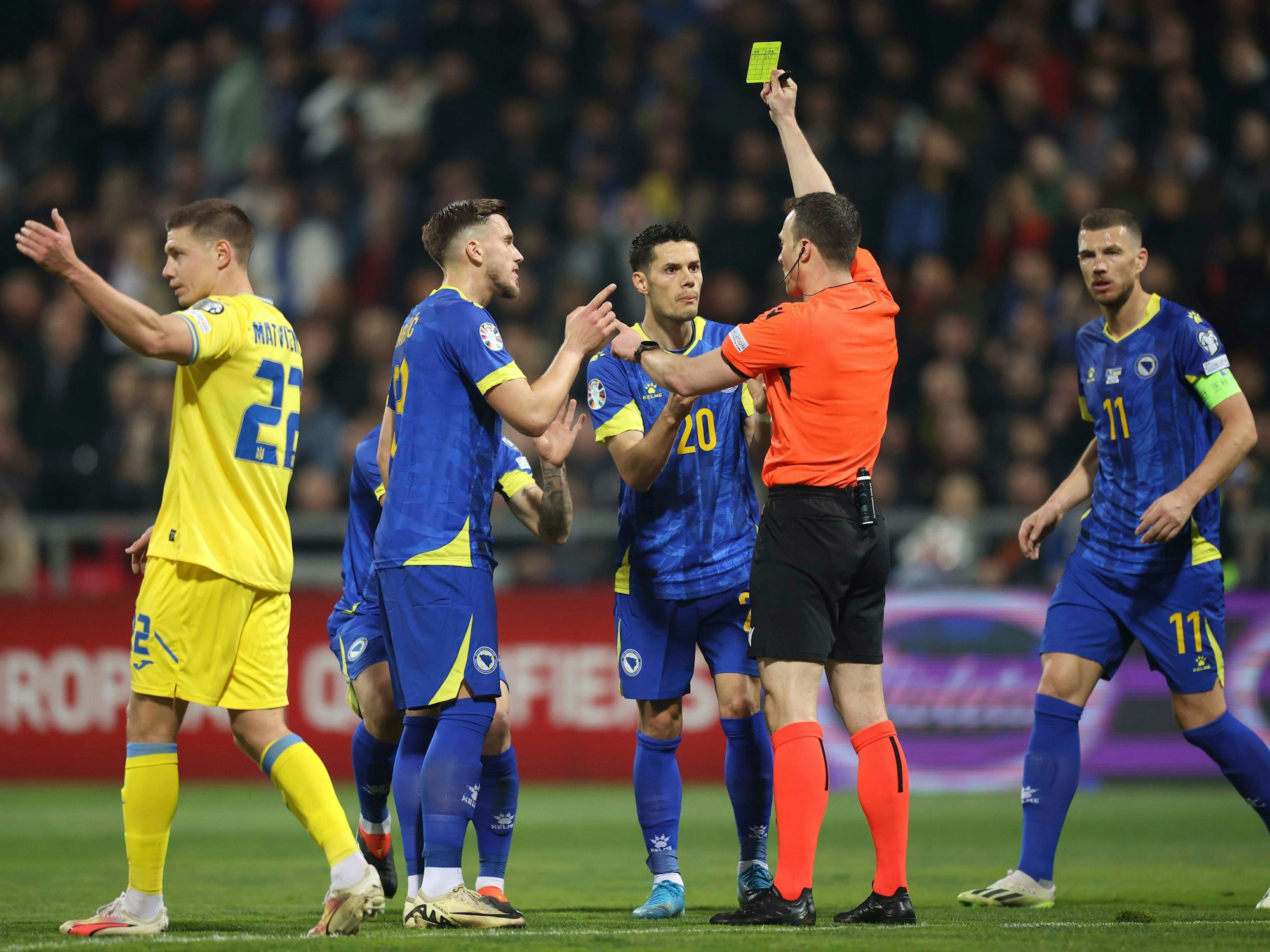 Die Spieler von Bosnien-Herzegowina beschweren sich im Spiel gegen die Ukraine (21. März 2024) über eine Gelbe Karte von Schiedsrichter Felix Zwayer.
