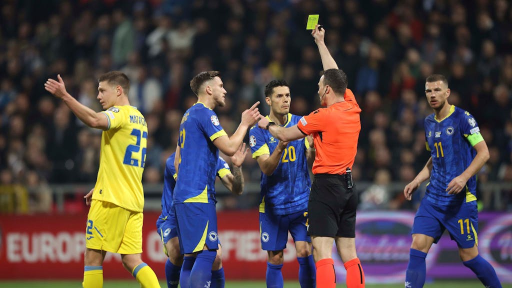 Die Spieler von Bosnien-Herzegowina beschweren sich im Spiel gegen die Ukraine (21. März 2024) über eine Gelbe Karte von Schiedsrichter Felix Zwayer.