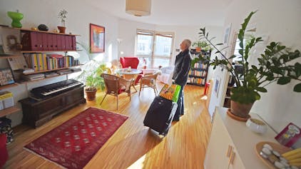 Ein Tourist, der eine Übernachtung über das Onlineportal Airbnb gebucht hat, kommt mit seinem Koffer in der gemieteten Wohnung an.