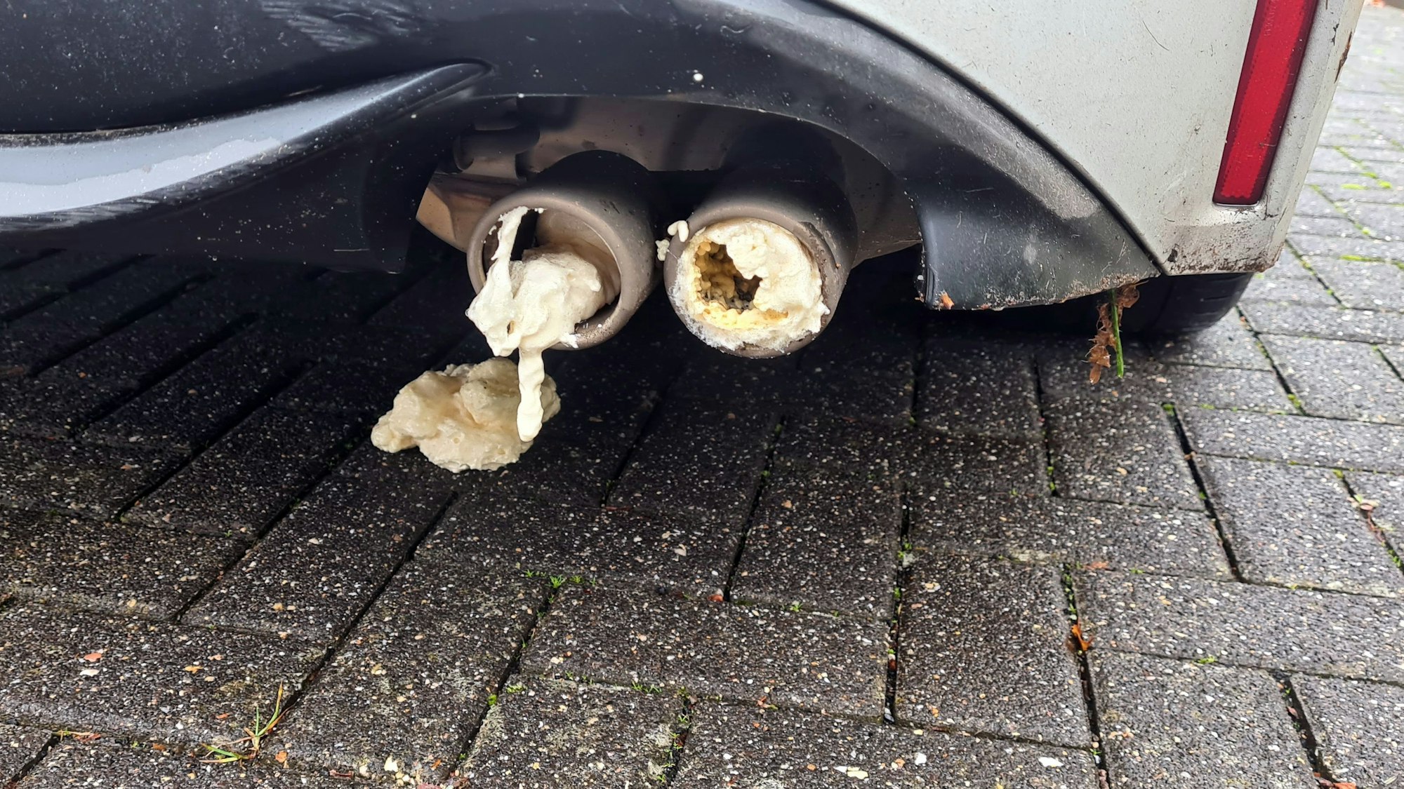 Der Doppelauspuff eines Autos ist mit Bauschaum ausgesprüht worden.