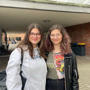 Zwei Schülerinnen stehen vor ihrer Schule