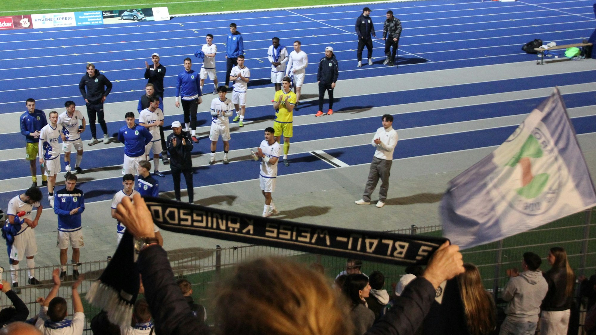 Enttäuschte Spieler stehen vor der Fankurve und applaudieren zum Dank für die Unterstützung den Fans zu.