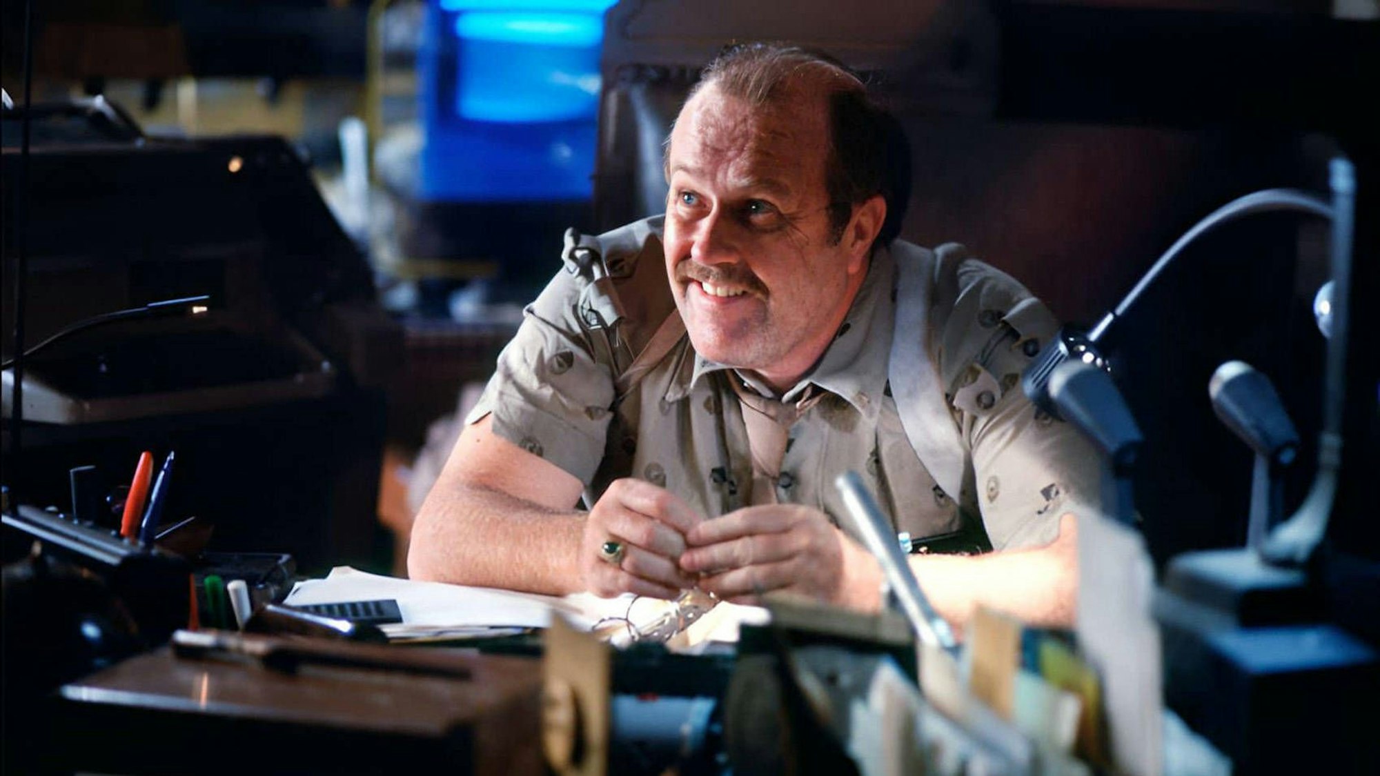 M. Emmet Walsh grinst als Polizeichef Bryant in Ridley Scotts „Blade Runner“ (1982) hinter seinem Schreibtisch.