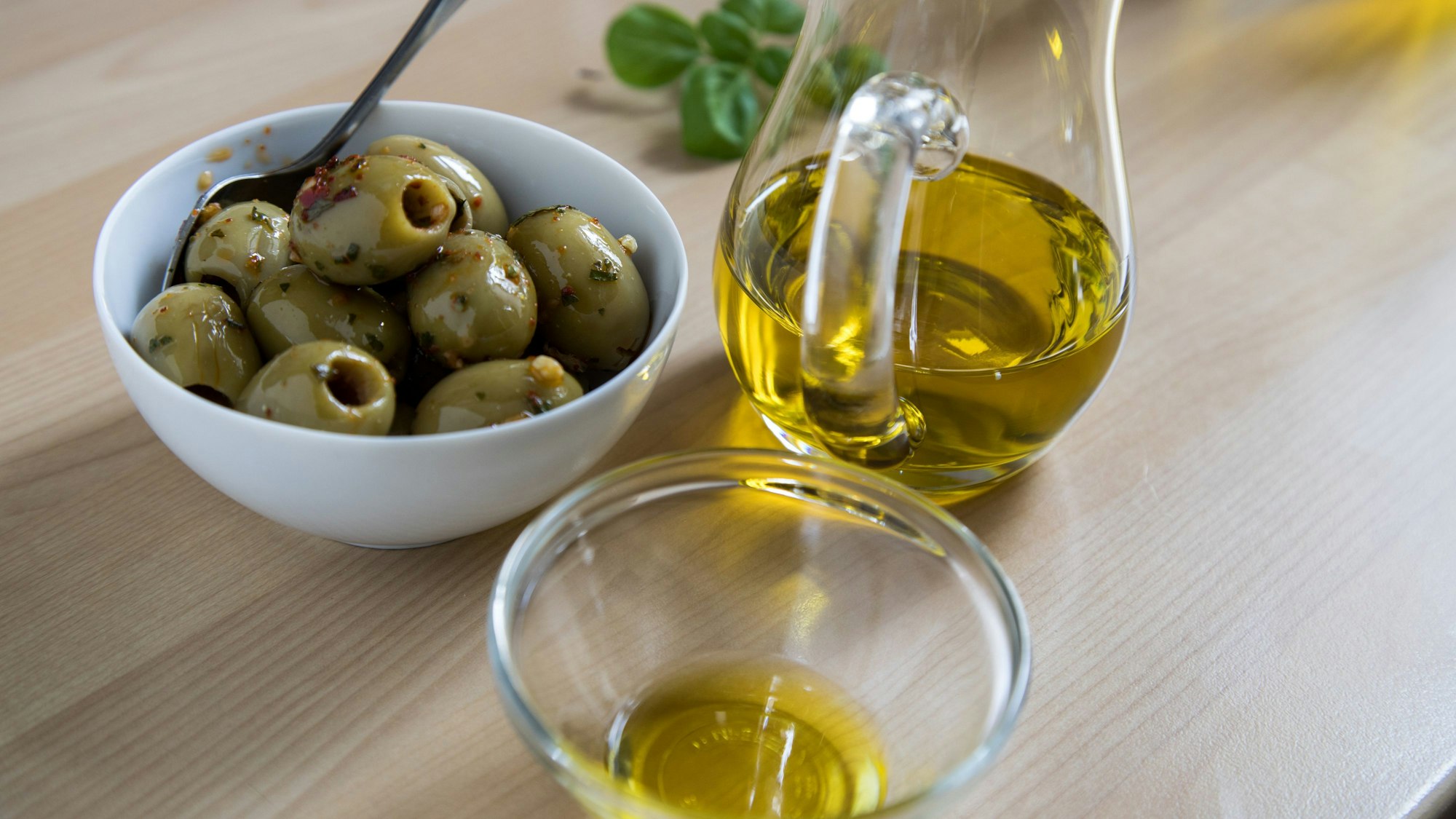 Olivenöl und Oliven stehen auf einem Tisch.