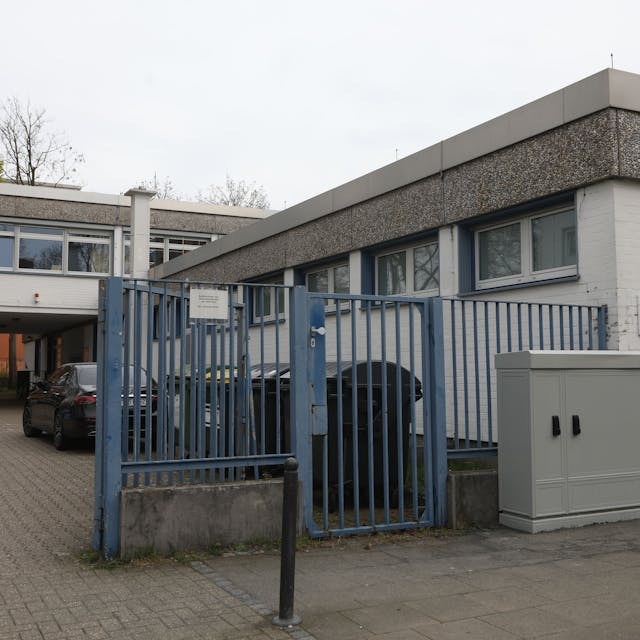 Zu sehen ist eine Kölner Kindertagesstätte von außen mit einem blauen Tor im Vordergrund.