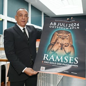 Mostafa Waziri hält in den Gängen des Odysseums Köln ein Plakat der Ausstellung "Ramses &amp; Das Gold der Pharaonen". Die Ausstellung ist ab 13. Juli 2024 zu Gast im Odysseum. Dr. Mostafa Waziri hat sich vor Ort ein Bild gemacht.&nbsp;