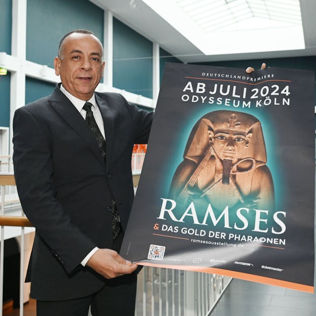 Mostafa Waziri hält in den Gängen des Odysseums Köln ein Plakat der Ausstellung "Ramses &amp; Das Gold der Pharaonen". Die Ausstellung ist ab 13. Juli 2024 zu Gast im Odysseum. Dr. Mostafa Waziri hat sich vor Ort ein Bild gemacht.&nbsp;
