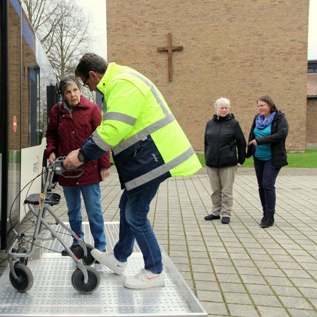 Ein Mitarbeiter der Rhein-Erft Verkehrsgesellschaft zeigt einer Senioren, wie sie ihren Rollator in den Bus heben kann.